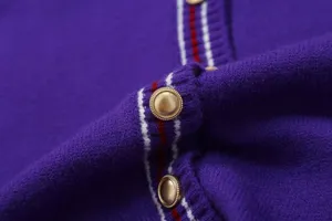 Close up view of purple knit cardigan with red white stripe trim and gold buttons detail.