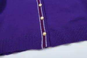 Purple knit cardigan detail featuring gold tone metal buttons and striped placket trim.
