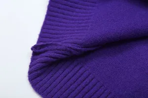 Close-up view of purple knitted sweater texture, showing fine ribbed hem and soft fabric.