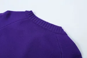 Close-up detail shot of the purple knit sweater shoulder and ribbed collar design texture.