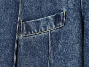 Close-up detail van damenspijkerjas zaklapje en contrasterende stiksels, blauwe stof.