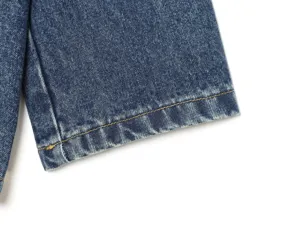 Mouwdetail van spijkerjas met klassieke gele contraststiksels en vintage blauwe wassing.