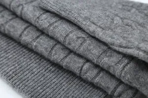 Grey knit sweater fabric detail, soft cable knit texture with ribbed hem for women.