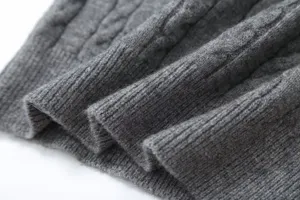 Close-up of grey cable knit sweater fabric showing soft texture and elastic ribbed details.