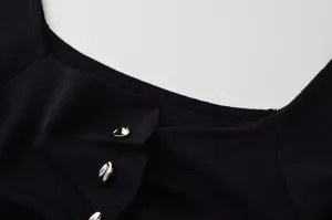 Vue détaillée d'un haut tricoté noir pour femme avec col carré et boutons argentés.