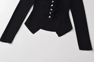 Gros plan du haut en tricot côtelé noir avec boutons métalliques et fronces.