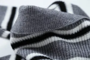 Primo piano della texture del tessuto del maglione in maglia a righe nero bianco e grigio.