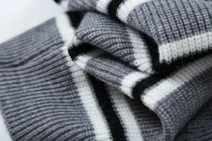 Primo piano dettagliato del maglione in maglia a righe da donna in grigio, bianco e nero.