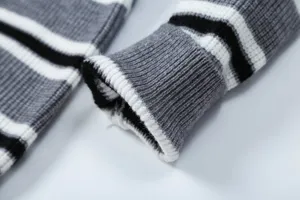Dettaglio manica maglione lavorato, motivo nero bianco grigio, capo di moda casual morbido.