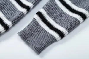Primo piano dettagliato della manica del maglione a righe grigio, bianco e nero fine.