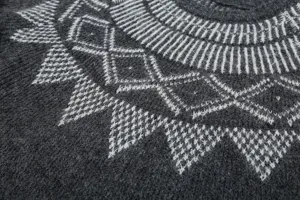 Primo piano di maglione in maglia grigio scuro con motivo jacquard geometrico bianco invernale