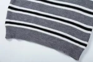 Primo piano di dettaglio dell'orlo in maglia a righe nero bianco e grigio del maglione.
