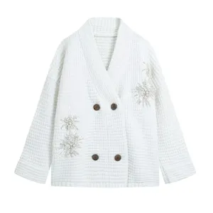 Close-up of white knitted cardigan with exquisite beading, V-neck and wooden buttons detail.