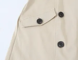 Beige trench dress fabric detail shot showing button and pocket flap design clearly.