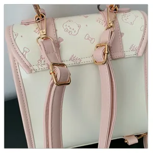 Chic cream and pink backpack with cute cat bow pattern, stylish school bag detail view.