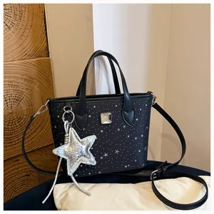 Dettaglio borsa nera con stampa di stelle, elegante motivo argentato e manici pratici.