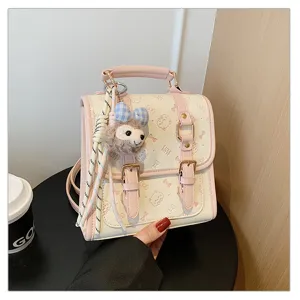 Detailed view of the cute pink leather backpack featuring a plush charm and double buckles.
