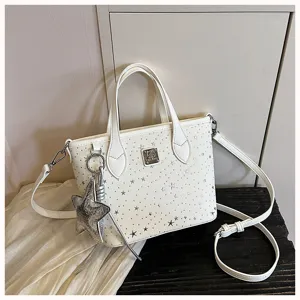 Vista dettagliata di una borsa da donna bianca con borchie a stella e bel ciondolo.
