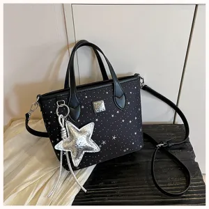Borsa tote nera con stampa di stelle, manici, tracolla e ciondolo a stella argentata.