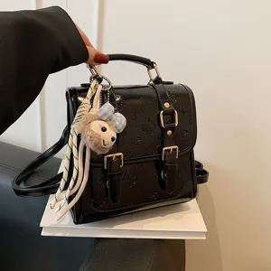 Black PU leather mini backpack with embossed details and cute plush keychain accessory.