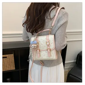 Detailed view of the cute pink and white backpack with plush pendant and bow patterns.