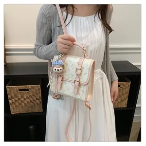 Preppy style backpack detail view featuring cute plush charm and pink buckle straps.
