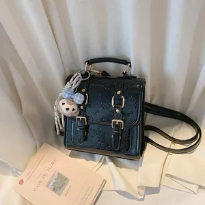 Black retro leather mini backpack with embossed pattern and cute plush charm detail.