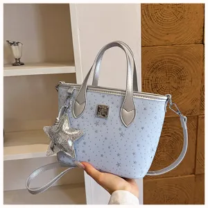 Dettaglio borsa a mano azzurra con stampa di stelle manici argentati e ciondolo a stella.