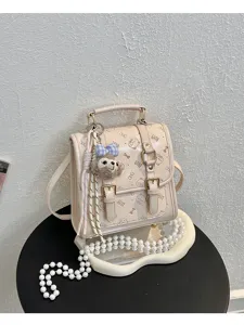 Detailed view of beige vintage backpack with cute plush charm and gold buckles, aesthetic design.