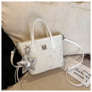 Borsa bianca con borchie a stella, manici, tracolla e ciondolo a forma di stella.