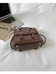 Detail view of brown vintage retro small backpack, dual buckle straps and embossed pattern.