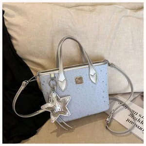 Borsa a mano azzurra con stampa di stelle, manici argentati e ciondolo a stella.