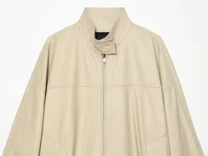 Detailopname van de kraag, de ritssluiting en de naden van het beige kunstlederen jasje.