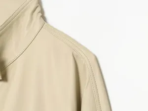 Close-up van de verfijnde schoudernaden van een stijlvol beige kunstlederen jack voor dames.