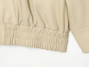 Beige kunstlederen jas detail close-up, elastische zoom en fijne stiksels erop.