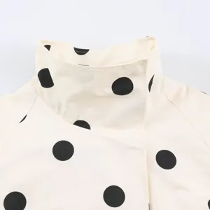 Close-up detail of women's chic black and white polka dot jacket stand collar design.