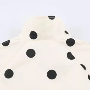 Detail view of cream womens bomber jacket with black polka dot print collar and shoulders.