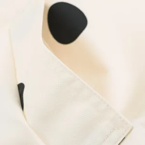 Close-up detail of beige jacket featuring black polka dot pattern and fine twill fabric.