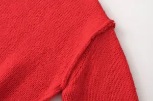 Nahaufnahme roter Strickpullover Detail, kuschelige Textur, stylischer asymmetrischer Kragen.