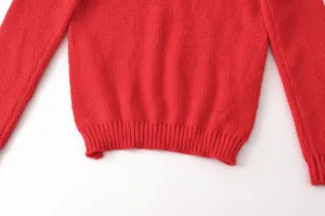 Detaillierte Ansicht eines kuscheligen roten Pullovers mit weicher Stricktextur und Bündchen.