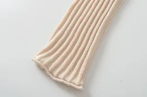 Close-up of women's ribbed knit sweater sleeve in soft apricot, clean detail view.