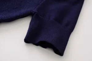 Primer plano del puño de un jersey de punto azul oscuro, con textura suave y canalé fino.
