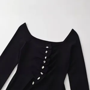 Pull noir à manches longues et col bateau moulant avec boutons élégants et plissés.