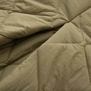 Close-up detail of olive green quilted fabric for women's winter coat apparel manufacturing