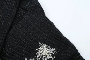 Black knit cardigan detail featuring sparkling metallic lurex thread and intricate pearl sequin embroidery.