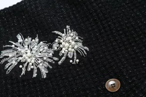 Detailed close-up shot of black knit fabric with exquisite pearl and sequin beaded embroidery.