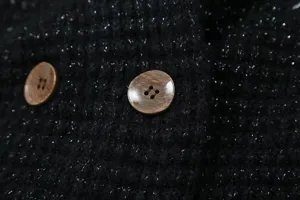 Close up detail of black metallic knit sweater fabric with vintage buttons, fashion style.