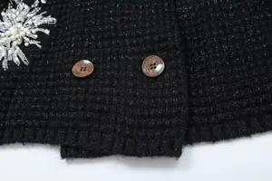 Black sparkly knitwear detail featuring exquisite beading embroidery and vintage brown buttons.