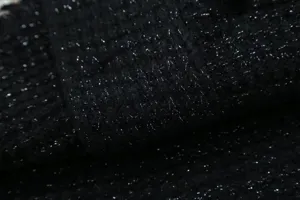 Black glitter knit sweater fabric detail showing soft texture and silver sparkle yarn.