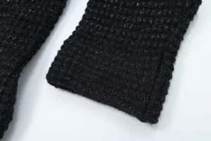 Close-up view of black knit sleeve detail with shimmering metallic threads for women sweater.